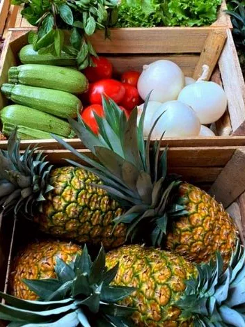 Cajas de madera con piñas, calabaza, cebolla y jitomate
